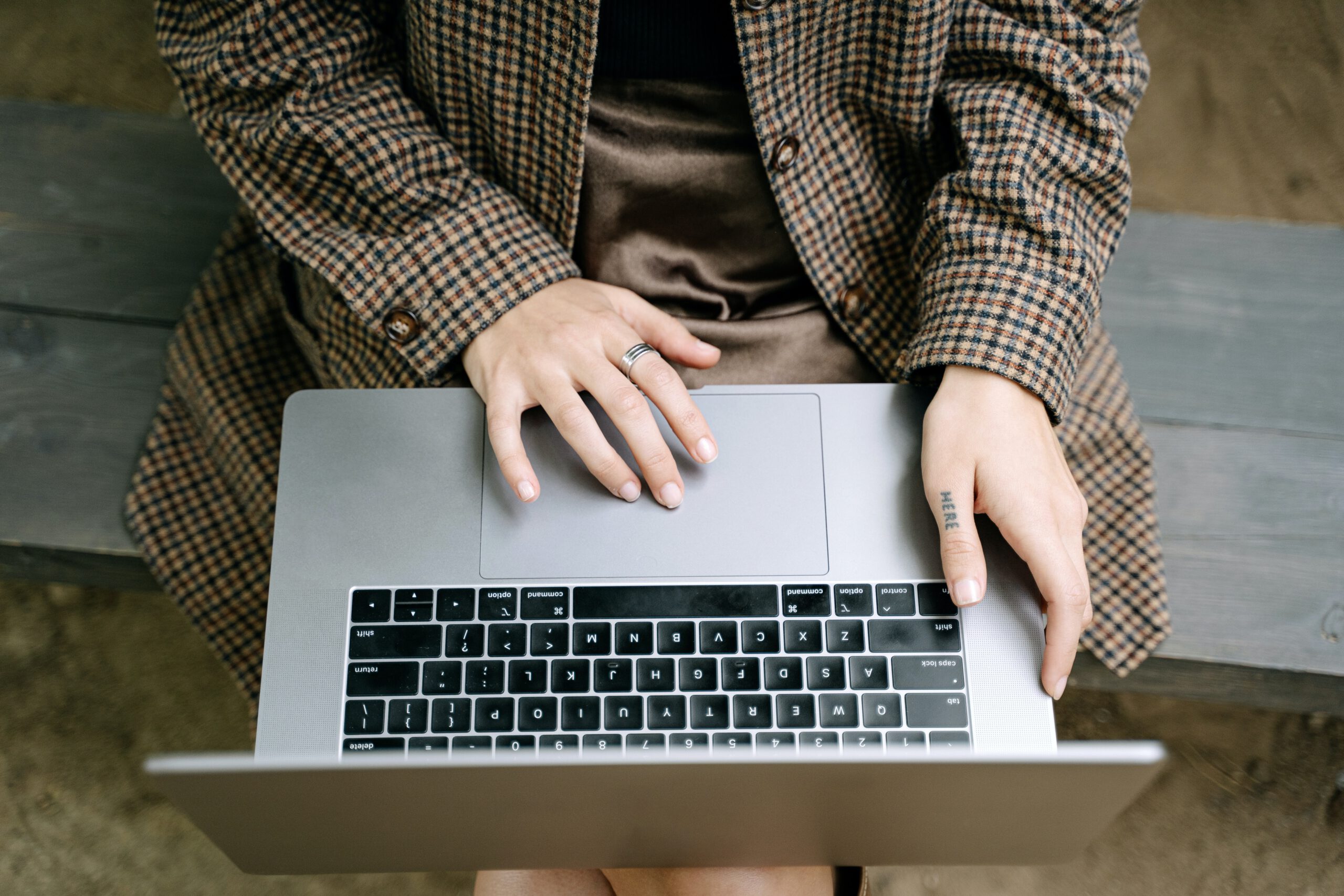 Mężczyzna w brązowym płaszczu w pepitkę pracujący na laptopie